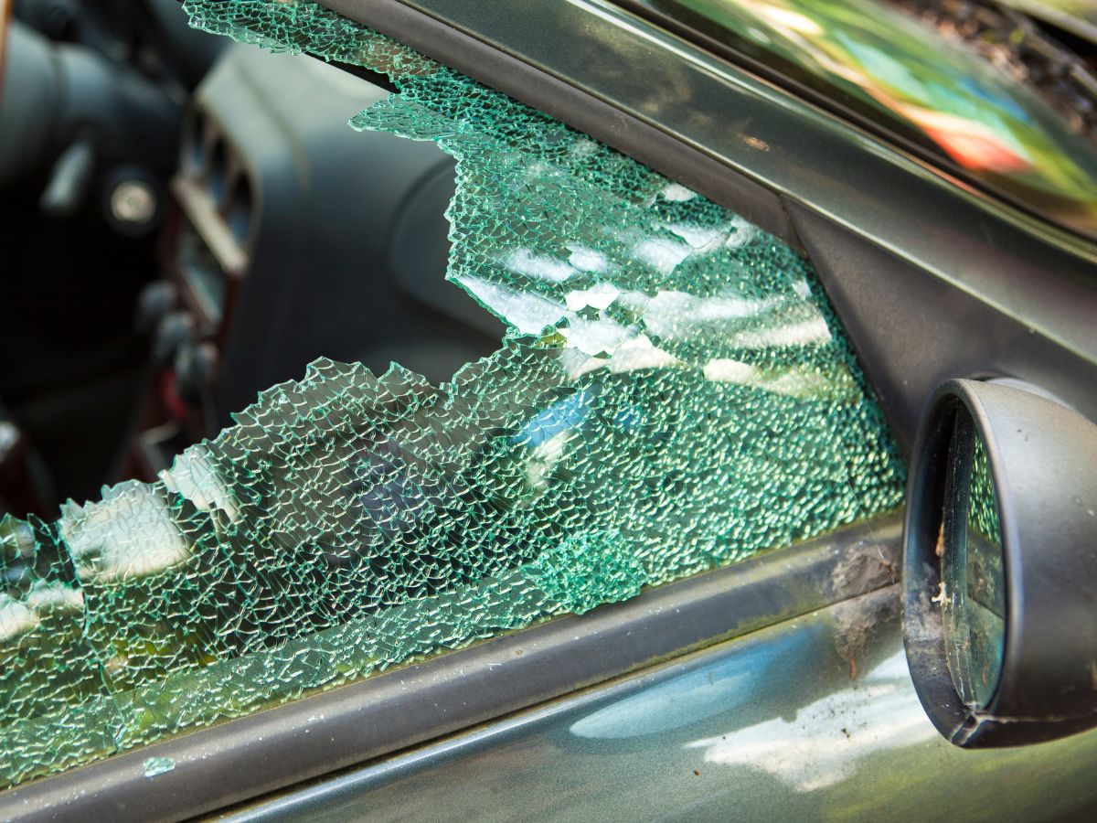 Smashed car side window with broken glass left in the door frame