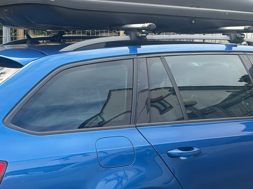 Rear side windows and quarter glass on a blue estate car with a roof box