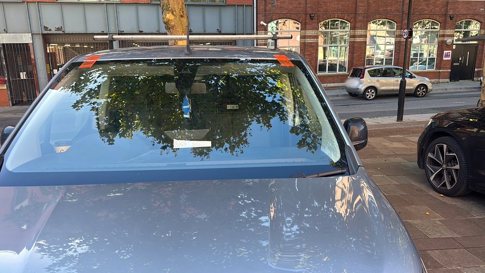 Technician fitting a new windscreen on a grey car