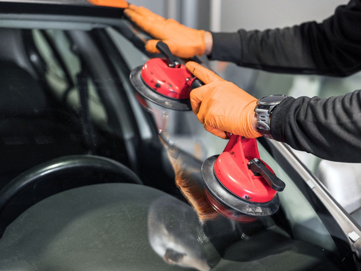 Windscreen fitter positioning a replacement windscreen with suction lifters